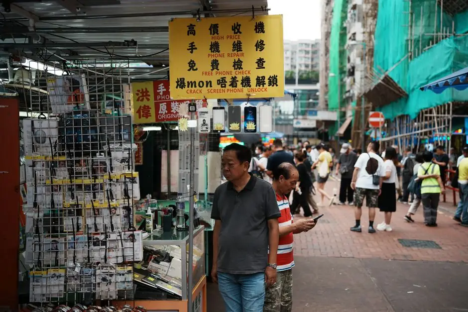 Lively street scene showcasing a phone repair shop and people walking by in an urban market environment.
